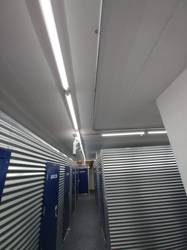 View of metal pipes containing new wiring running along the ceiling making a right angle down a hallway